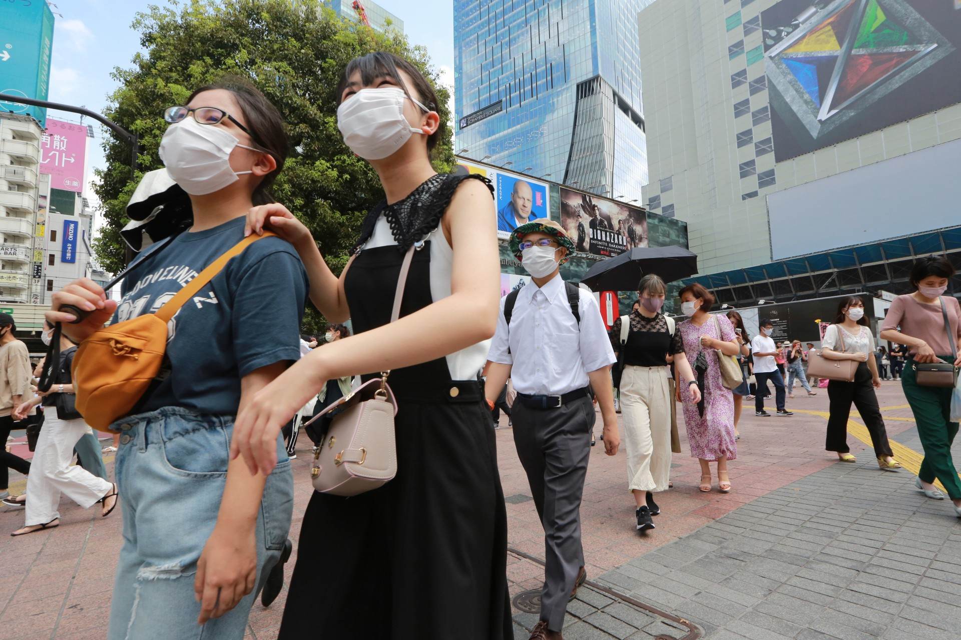 Com máscaras de proteção, japoneses caminham por rua de Tóquio Com máscaras de proteção, japoneses caminham por rua de Tóquio