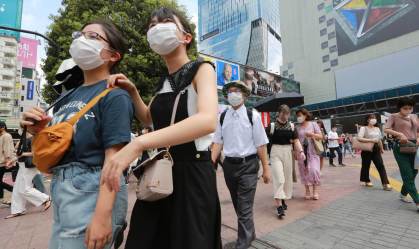 Com máscaras de proteção, japoneses caminham por rua de Tóquio