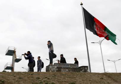 Pessoas tiram fotos ao lado da bandeira afegã em Cabul, Afeganistão