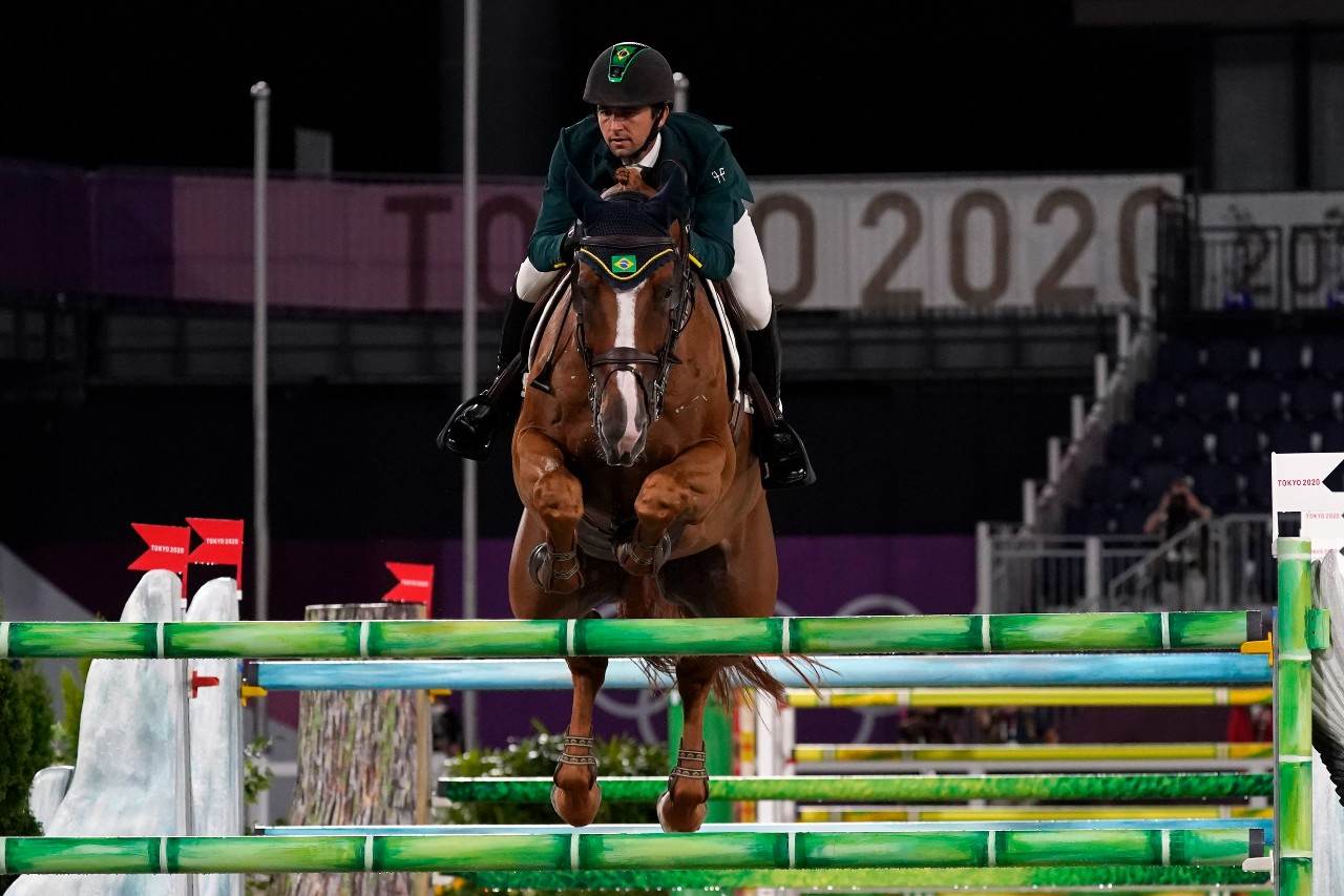 Atleta brasileiro do hipismo em cima do cavalo saltando obstáculo no Japão