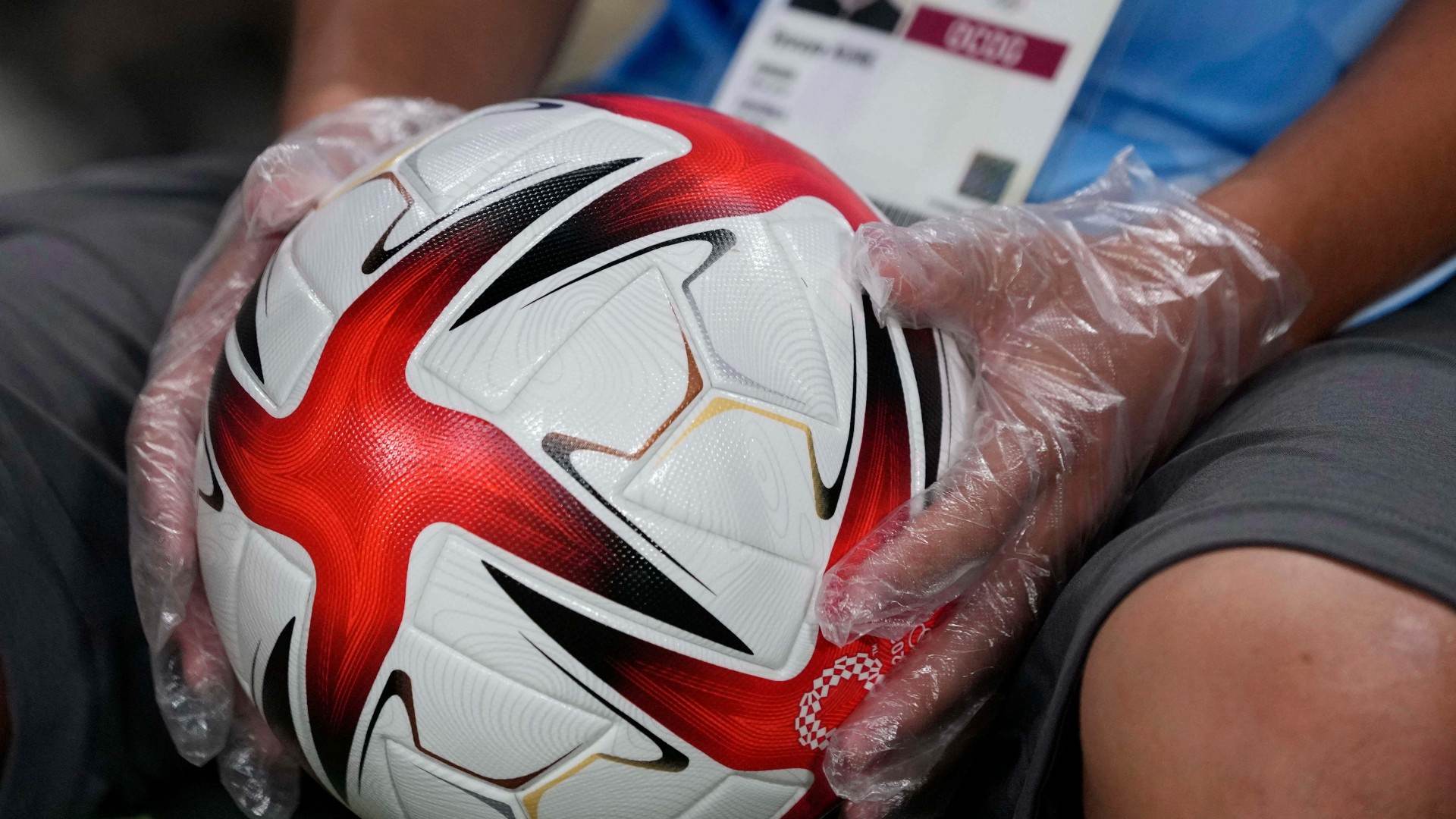 Voluntário em Tóquio usa luvas para segurar bola de futebol nos Jogos Voluntário em Tóquio usa luvas para segurar bola de futebol nos Jogos