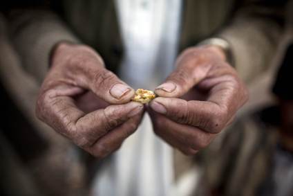 Homem afegão segura uma pequena peça de ouro, garimpada do local de uma mina pro