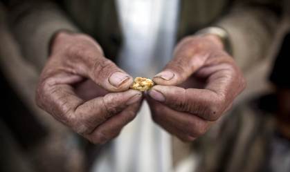 Homem afegão segura uma pequena peça de ouro, garimpada do local de uma mina pro