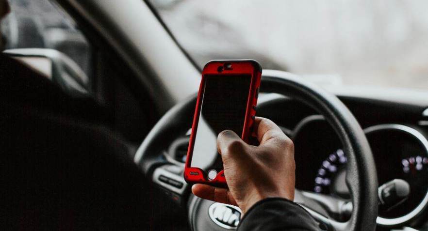 Motorista usando celular / Unsplash/Melissa Mjoen