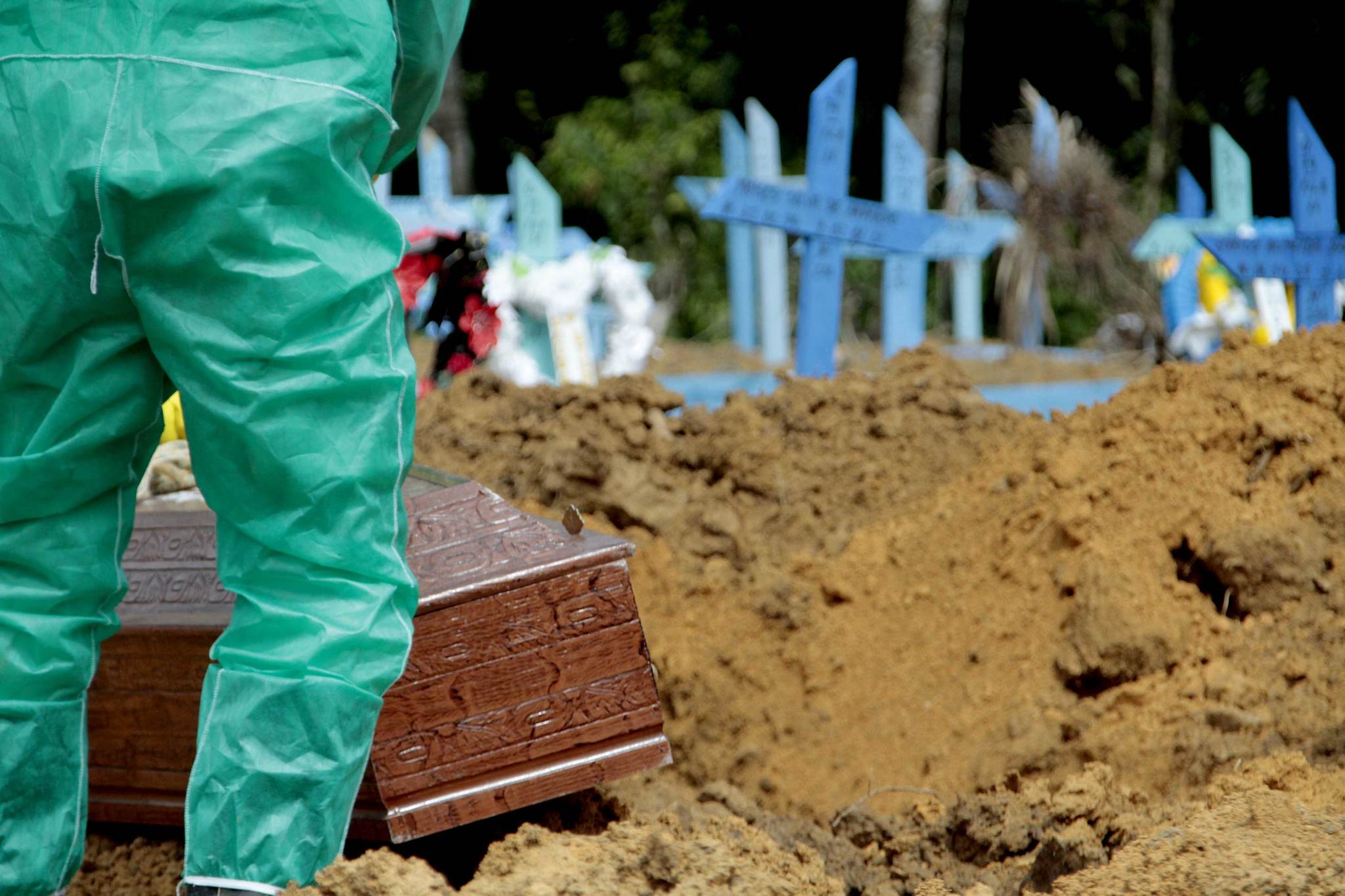 Coveiro em traje de proteção sepulta caixão em cemitério de Manaus Coveiro em traje de proteção sepulta caixão em cemitério de Manaus