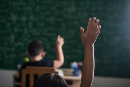 Criança levantando a mão em uma sala de aula