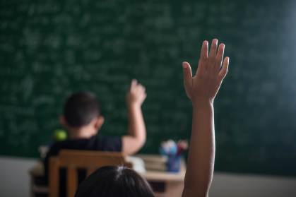 Criança levantando a mão em uma sala de aula