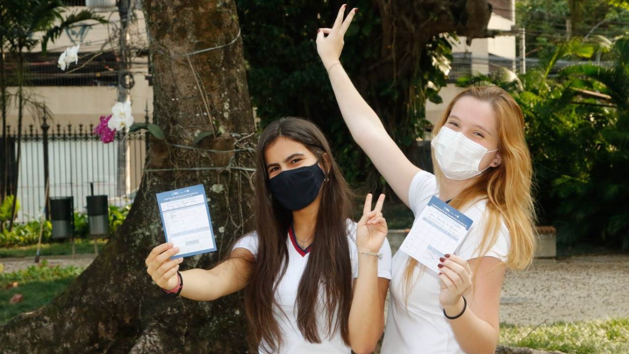 Estudantes exibem caderneta de vacinação após serem vacinadas contra Covid-19 no Rio de Janeiro