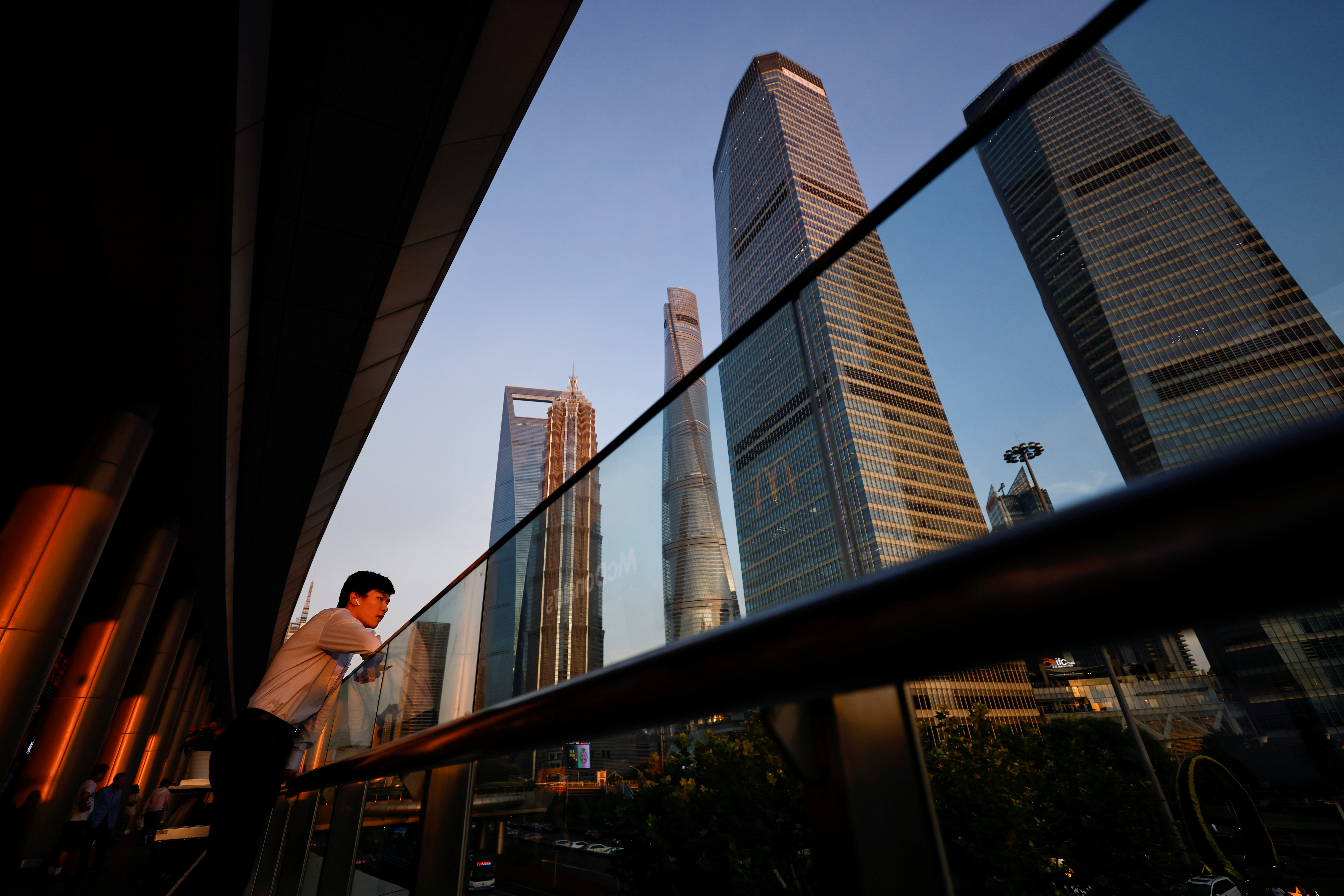 Homem com fones de ouvido no distrito financeiro de Lujiazui durante o pôr do sol em Pudong, Xangai, China, em 13 de julho de 2021. REUTERS/Aly Song