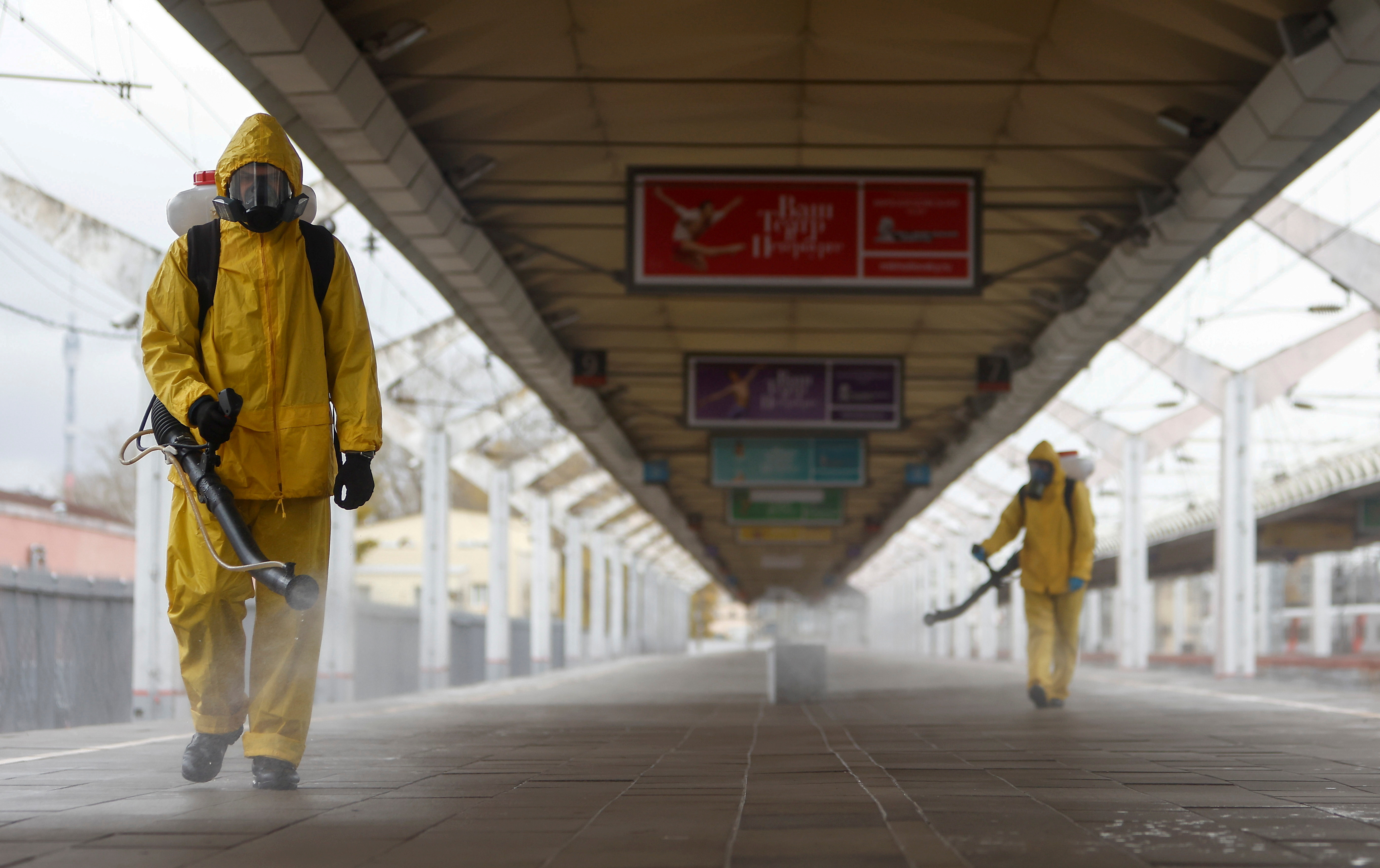 Especialistas em trajes de proteção desinfetam estação ferroviária em Moscou