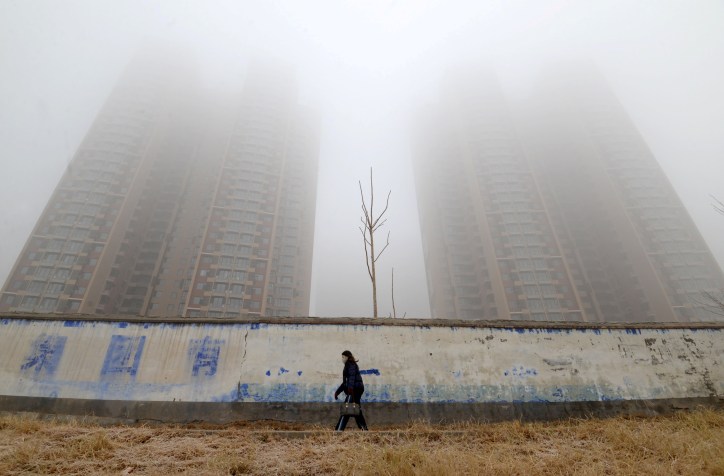 Mulher usando máscara caminha perto de prédios em meio à poluição em Hebei, na China / REUTERS/Stringer