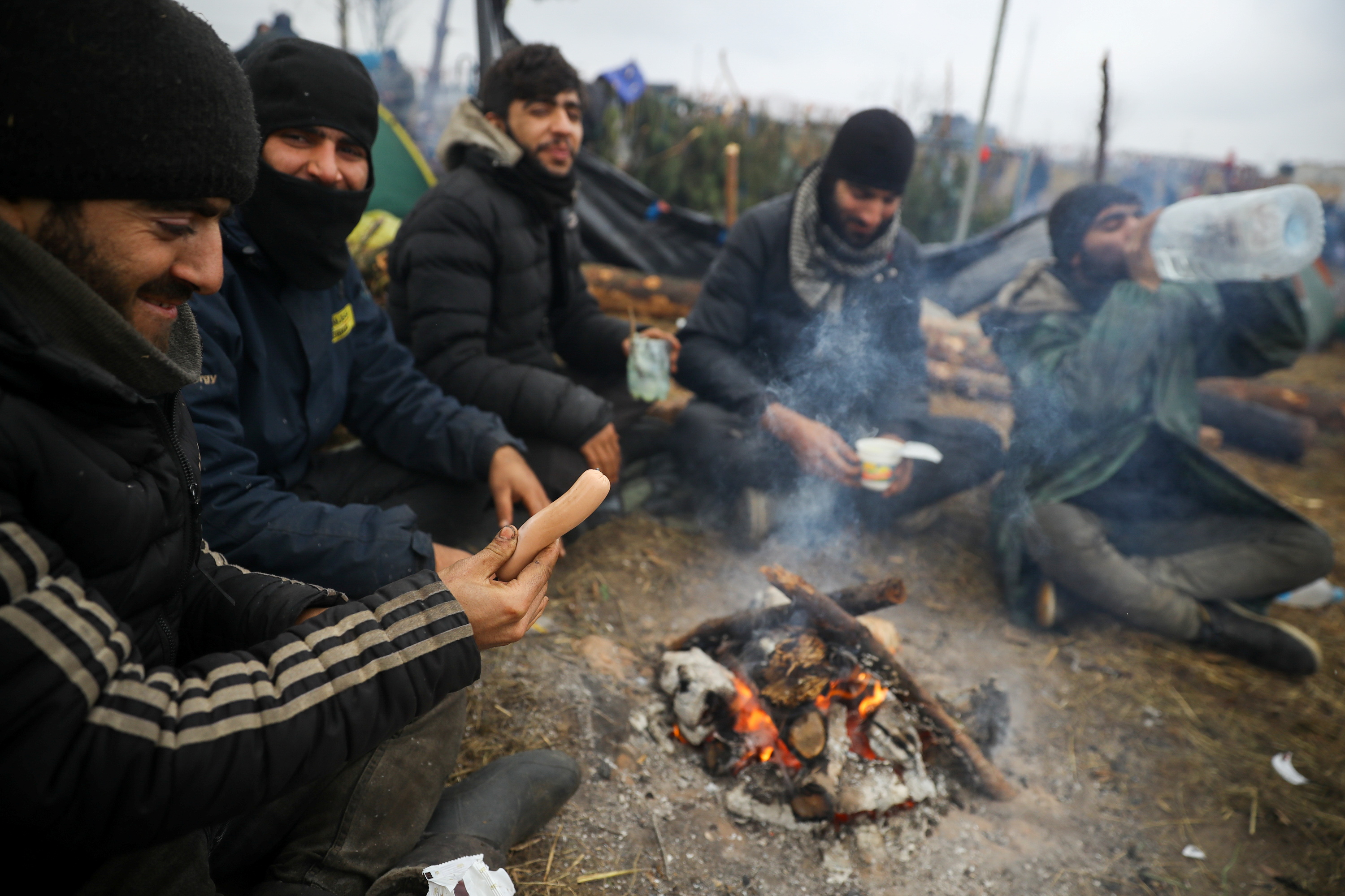 Imigrantes tentam se aquecer perto do posto de checagem de fronteira Kuznica-Bruzgi, entre Belarus e Polônia, em 18 nov. 2021 / REUTERS/Kacper Pempel