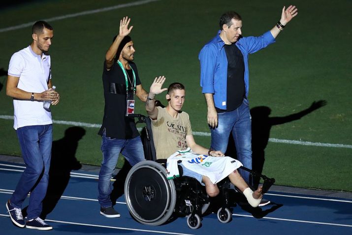 Quatro dos seis sobreviventes da tragédia da Chapecoense são homeageados em amistoso no Rio. Jackson Follmann (na cadeira de rodas), Alan Ruschel (atrás de Follman), Neto (à esquerda) e o jornalista Rafael Henzel (à direita), desfilaram antes da partida entre Brasil e Colômbia, em memória às vítimas do acidente, no dia 25 de janeiro de 2017 / Buda Mendes/Getty Images