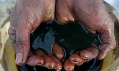 Funcionário segura amostra de petróleo.