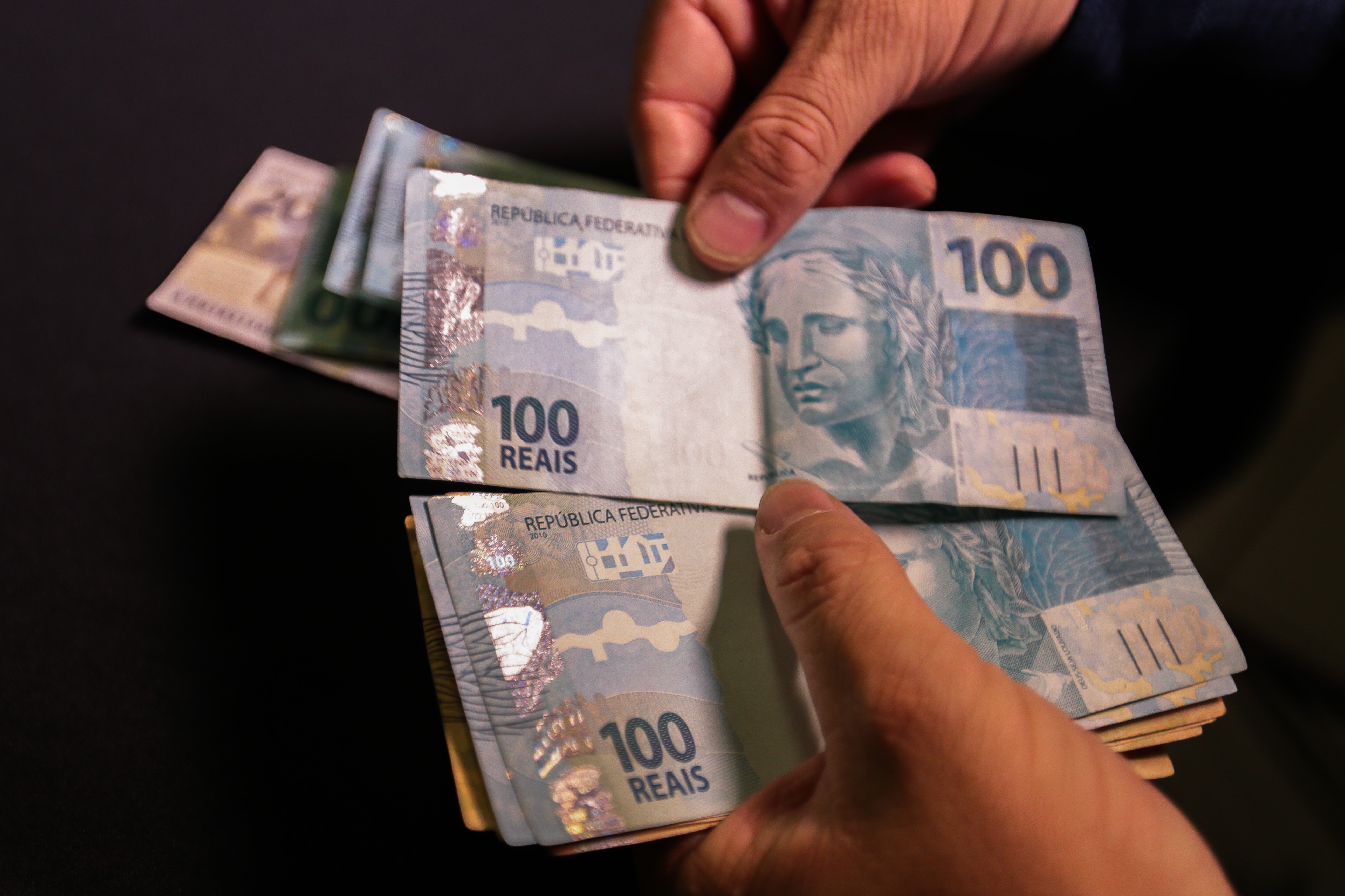Pessoa manuseando notas de real - 100 reais
