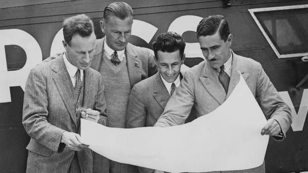 A tripulação de quatro homens do monoplano Southern Cross estuda um mapa de sua rota no aeroporto de Croydon em junho de 1930. Da esquerda para a direita: o aviador australiano Charles Kingsford Smith, o copiloto Evert Van Dyke, o operador de rádio John Stannage e o navegador J. Patrick Saul / Keystone/Hulton Archive/Getty Images
