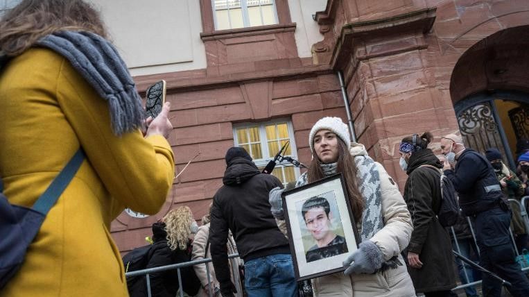 A ativista síria Samaa Mahmoud mostra uma foto de seu tio, Hayan Mahmoud, enquanto ela e outros esperam do lado de fora do tribunal em Koblenz, no oeste da Alemanha, na quinta-feira (13) / Bernd Lauter/AFP/Getty Images