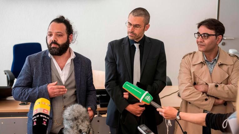 O advogado Patrick Kroker, ao centro, e os co-autores Wassim Mukdad, à esquerda, e Hussein Ghrer, à direita, respondem às perguntas dos jornalistas fora do tribunal em Koblenz, Alemanha, no início do julgamento em abril de 2020 / Thomas Lohnes/AFP/Getty Images