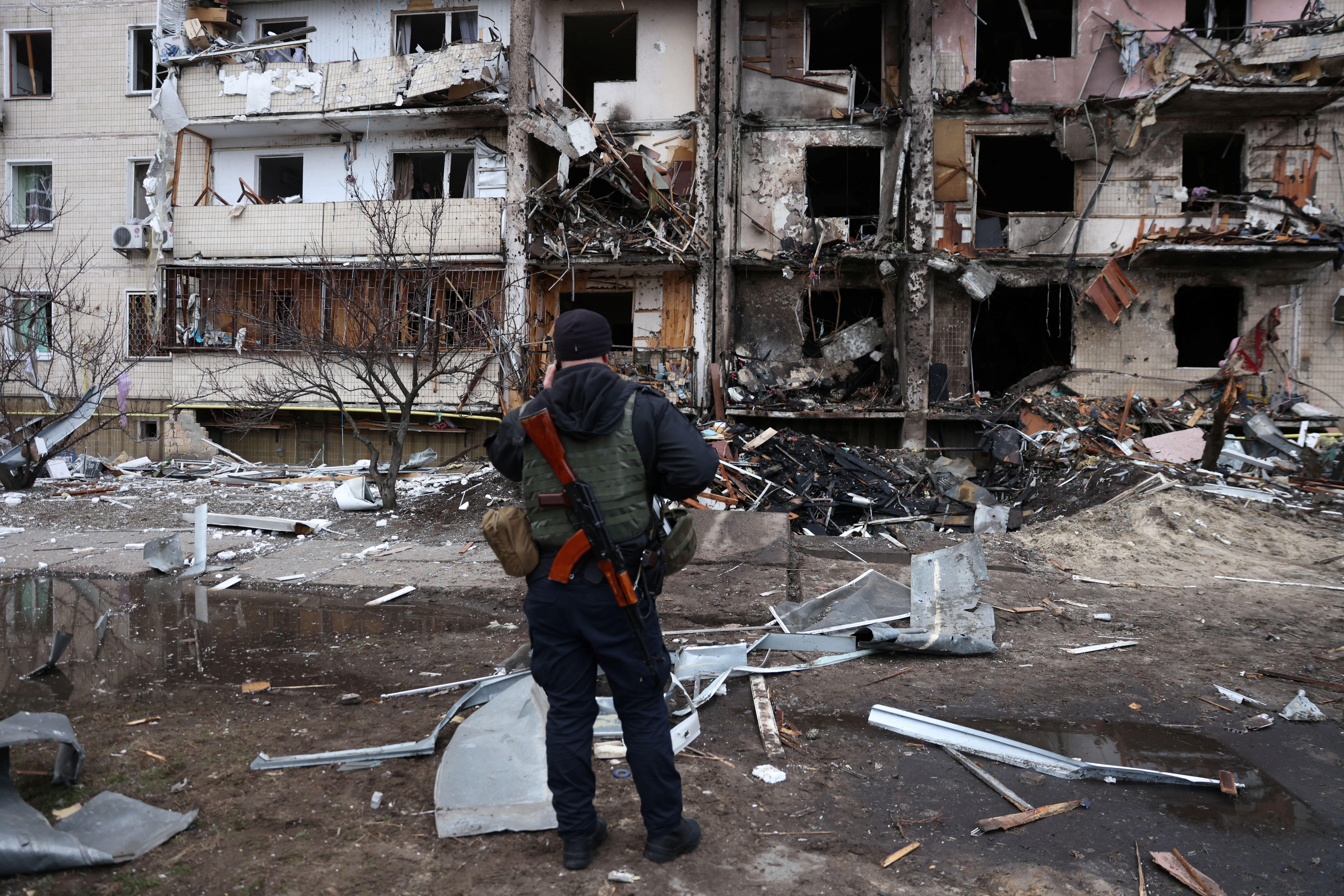 Homem em frente a prédio residencial danificado após a Rússia lançar um ataque maciço à capital ucraniana, Kiev