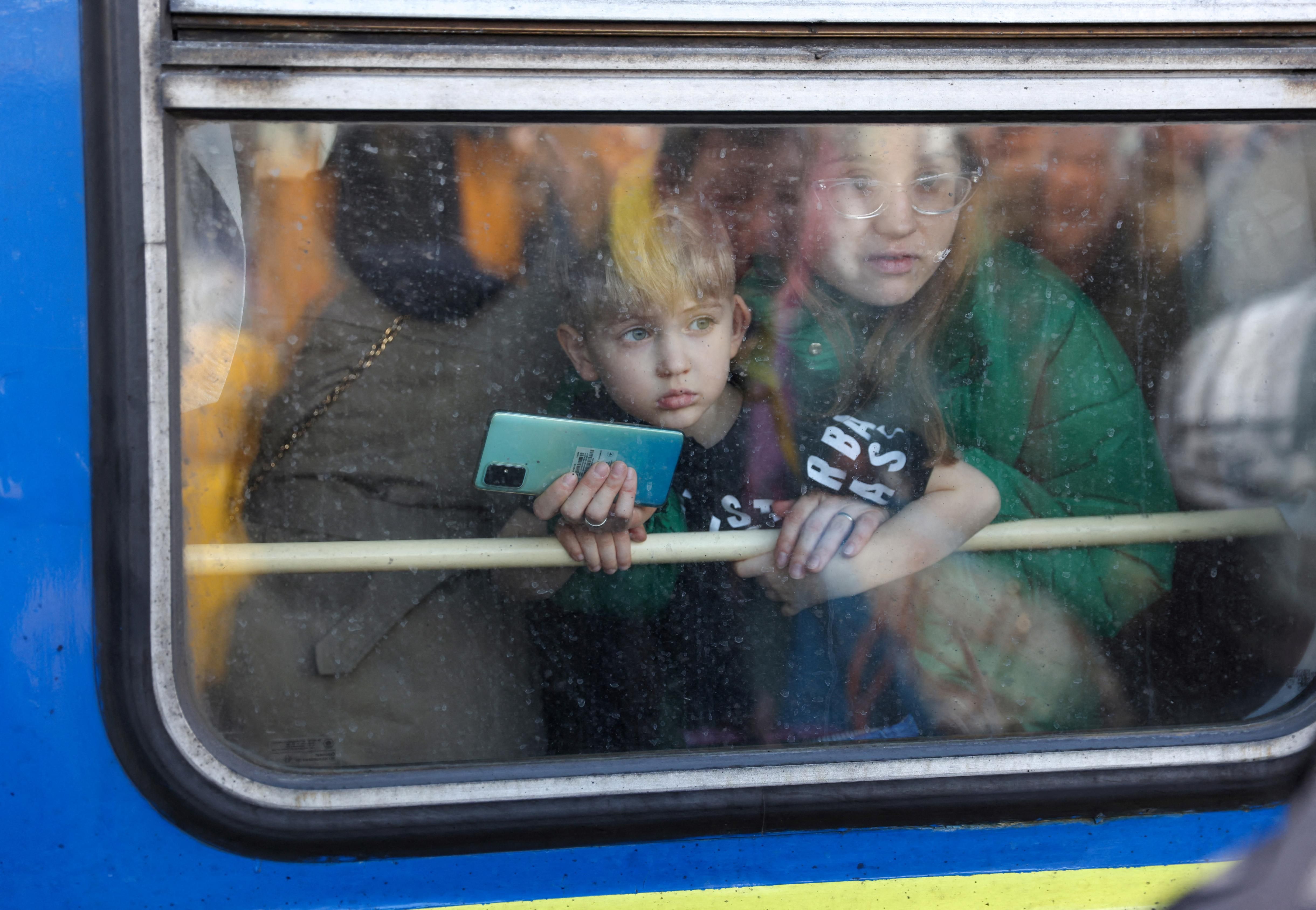 Mãe e filho observam multidão dentro de um trem, saindo da estação de Kiev, na Ucrânia, em 25 de fevereiro