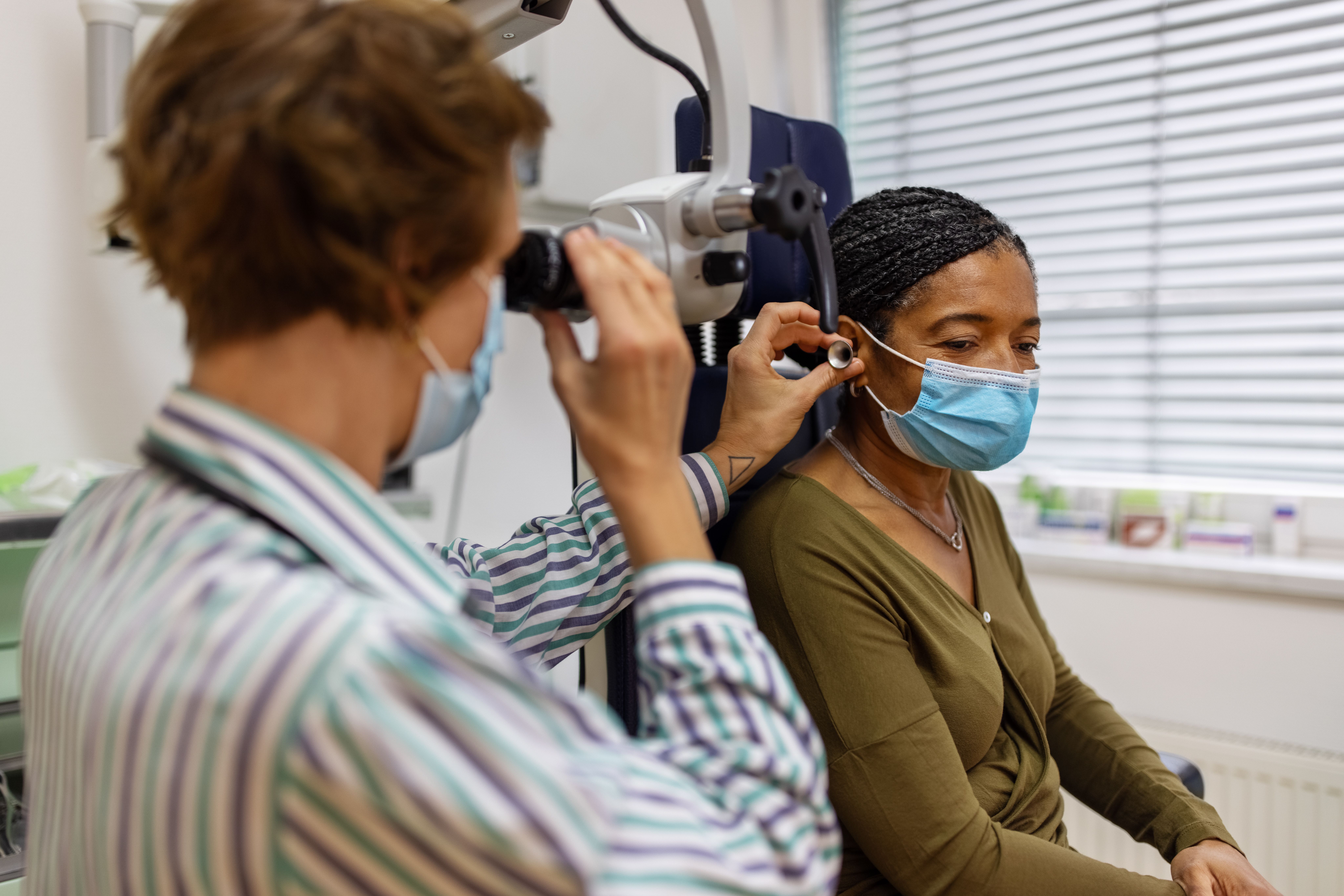 Doctor examining the ear of a senior woman in clinic