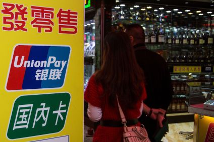Visitantes chineses passam por uma placa da China UnionPay do lado de fora de uma casa de penhores em Macau, em 20 de novembro de 2013