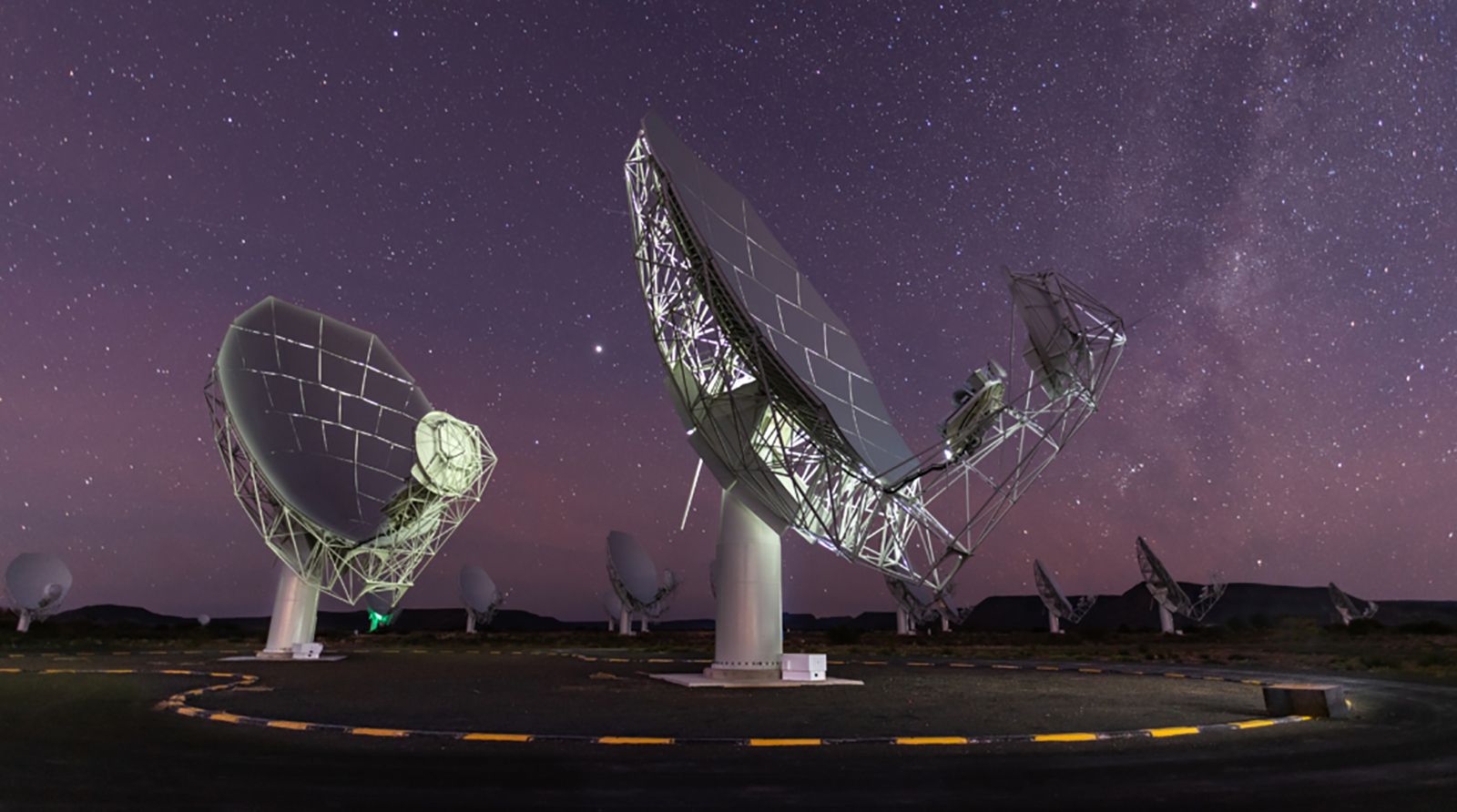 Os pratos do radiotelescópio MeerKAT podem ser vistos sob um céu cheio de estrelas em Karoo, África do Sul. / © SARAO
