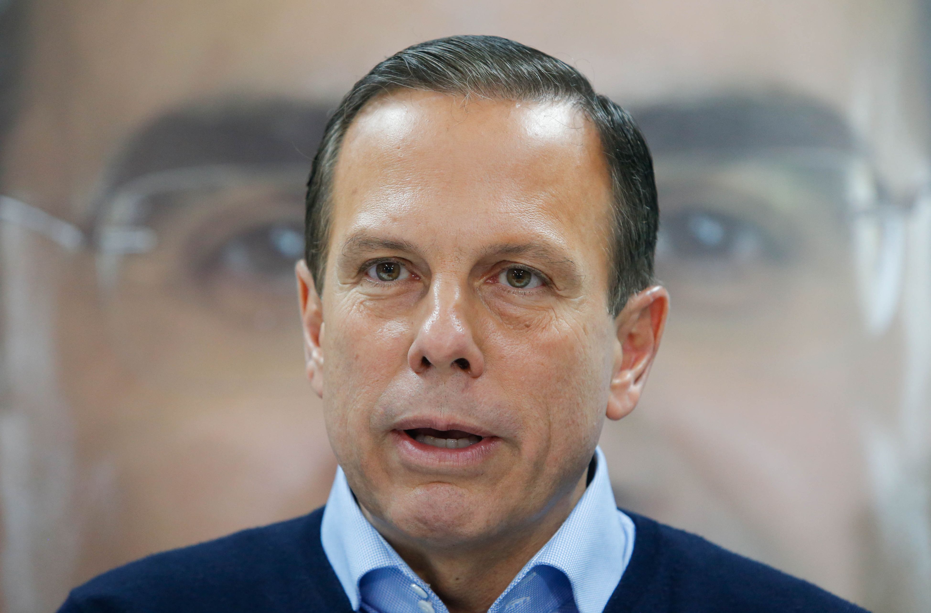 Governador de São Paulo, João Doria, em frente a banner com a foto do vice Rodrigo Garcia