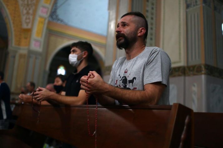 Descendentes de ucranianos e membros da “Irmandade dos Cossacos” oram o rosário dentro da igreja de São Josafá / Pilar Olivares/Reuters (3.mar.2022)