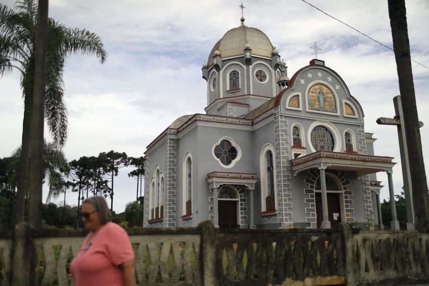 Mulher caminha em frente a uma igreja em Prudentópolis/ Pilar Olivares/Reuters (25.fev.2022)