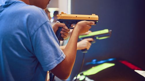 Teenage friends shooting with pistols in an amusement arcade