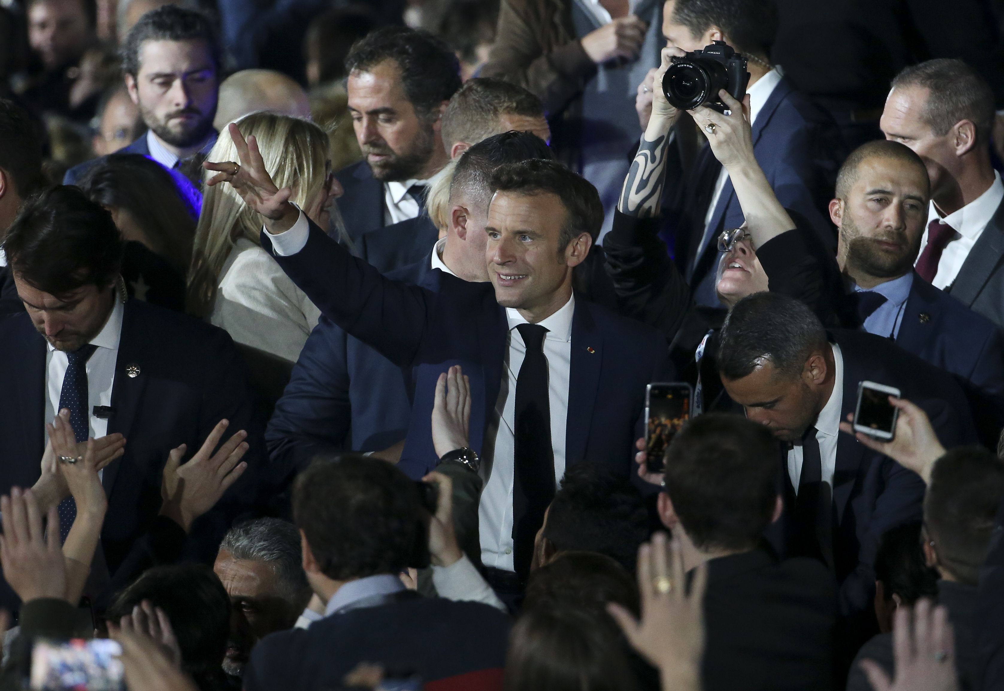 Emmanuel Macron acena para o público após ser reeleito presidente da França