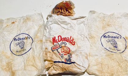 Casal encontra duas embalagens de hambúrguer e uma porção de batatas fritas em uma sacola do McDonald's atrás da parede do banheiro