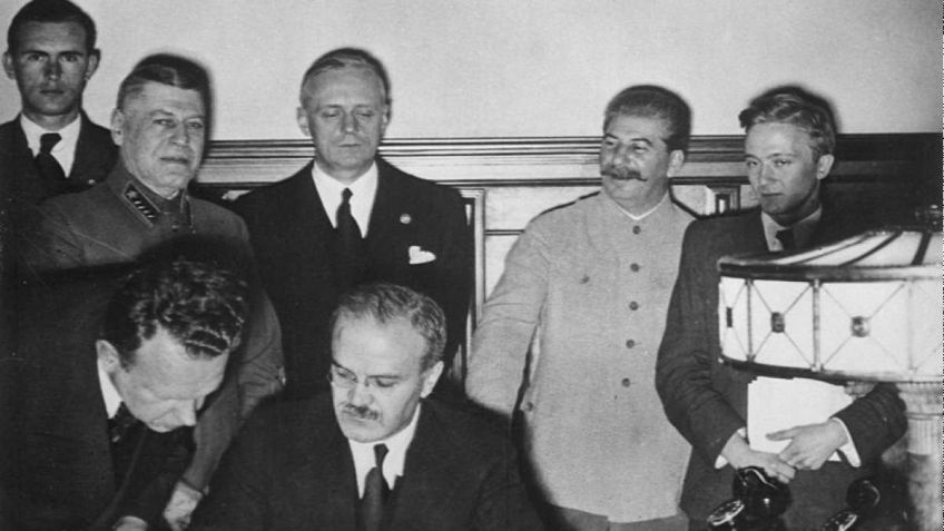 Ministros das Relações Exteriores de Alemanha e URSS, Ribbentrop e Molotov, assinam acordo, com Stalin ao fundo / Wikimedia Commons