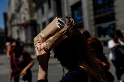 Uma mulher cobre a cabeça com uma bolsa durante um dia quente na Espanha. Junho de 2022