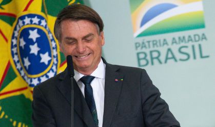 Presidente Jair Bolsonaro (PL) diante de painel com o logo do governo federal
