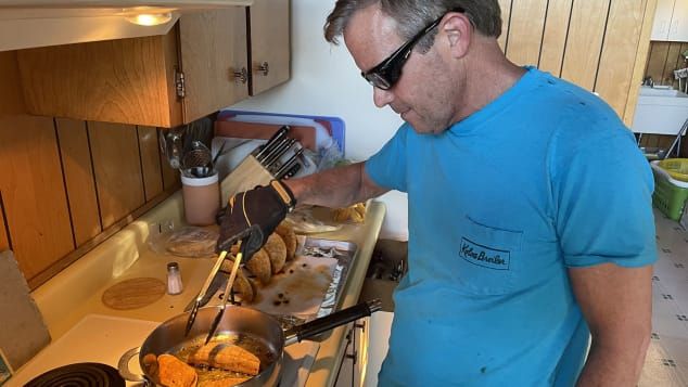 John "Wedge" Wardlaw frita tacos na noite de terça-feira em seu equipamento de proteção. / Paul Vercammen/CNN