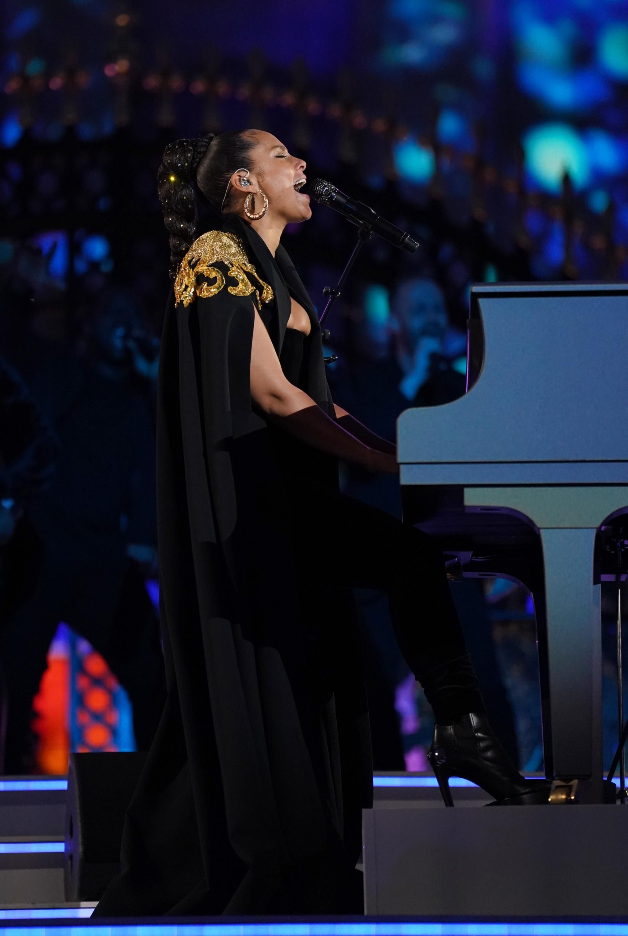 Alicia Keys se apresentou com uma capa preta dourada e um vestido de veludo da Moschino na Platinum Party at the Palace / Getty Images