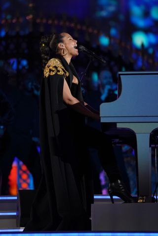Alicia Keys se apresentou com uma capa preta dourada e um vestido de veludo da Moschino na Platinum Party at the Palace / Getty Images