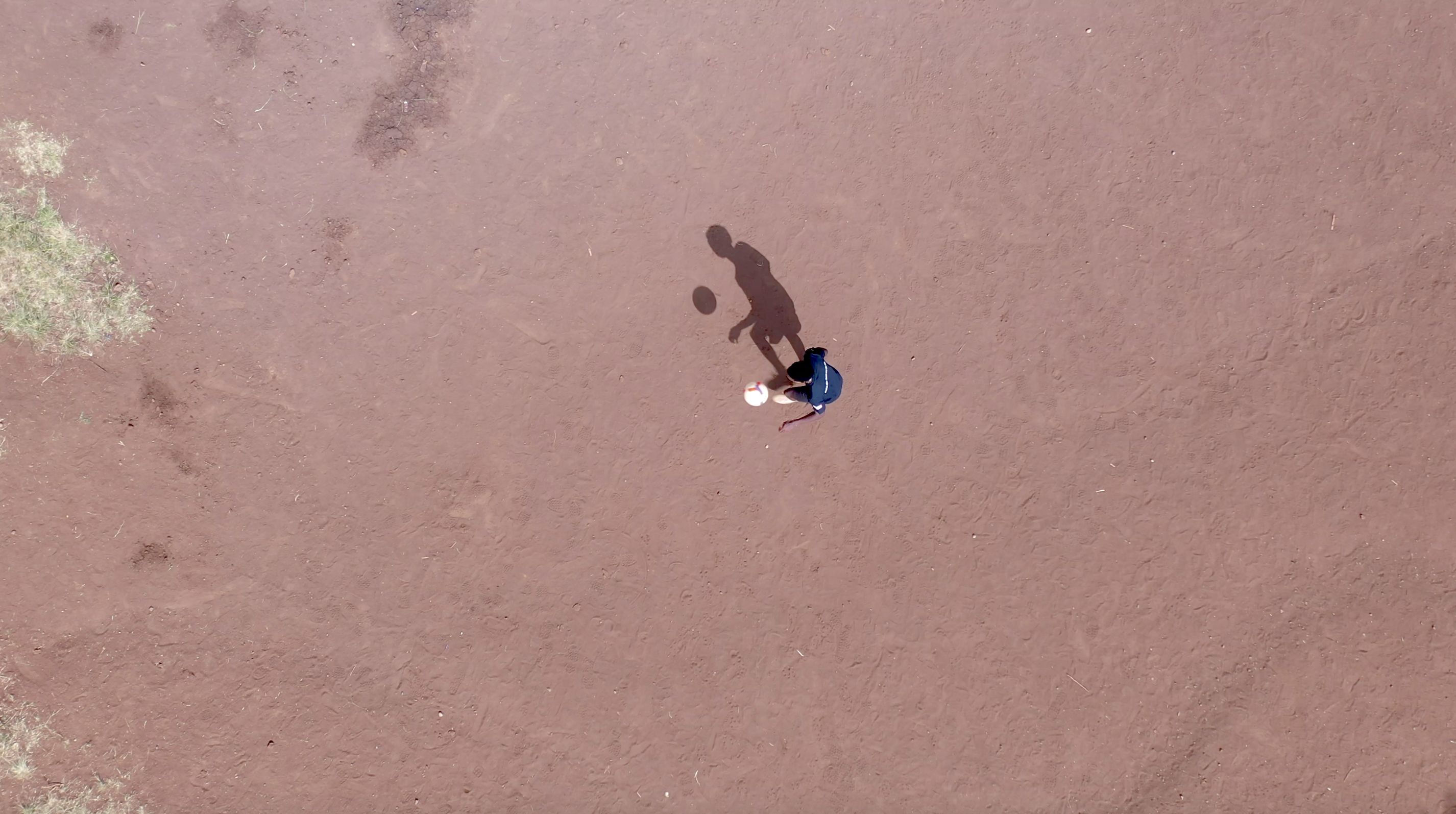 Mutunkei pratica suas habilidades de futebol em um pedaço de terra estéril. / CNN