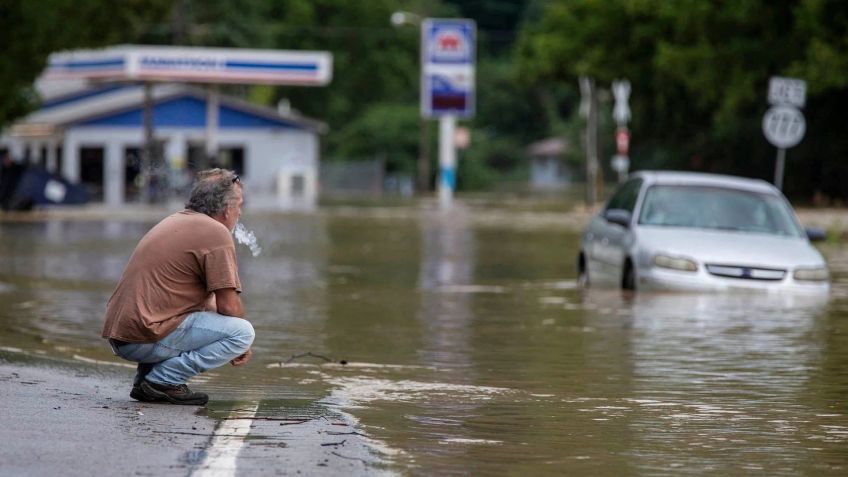 Homem observa seu carro preso na enchente / USA Today via Reuters