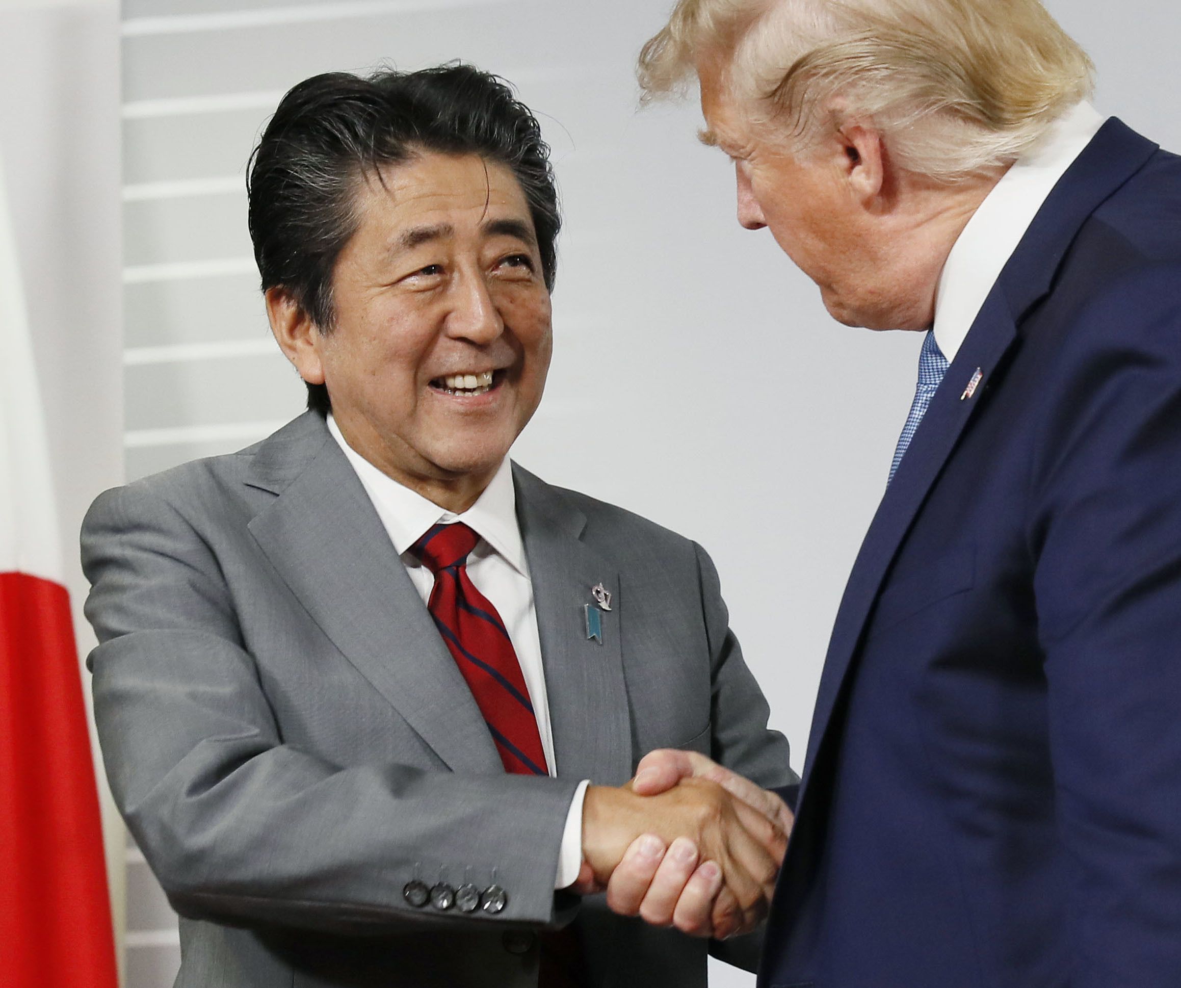 Primeiro-ministro Shinzo Abe cumprimenta Donald Trump em encontro bilateral do G7, em agosto de 2019, na França. / Kyodo News Stills via Getty Imag