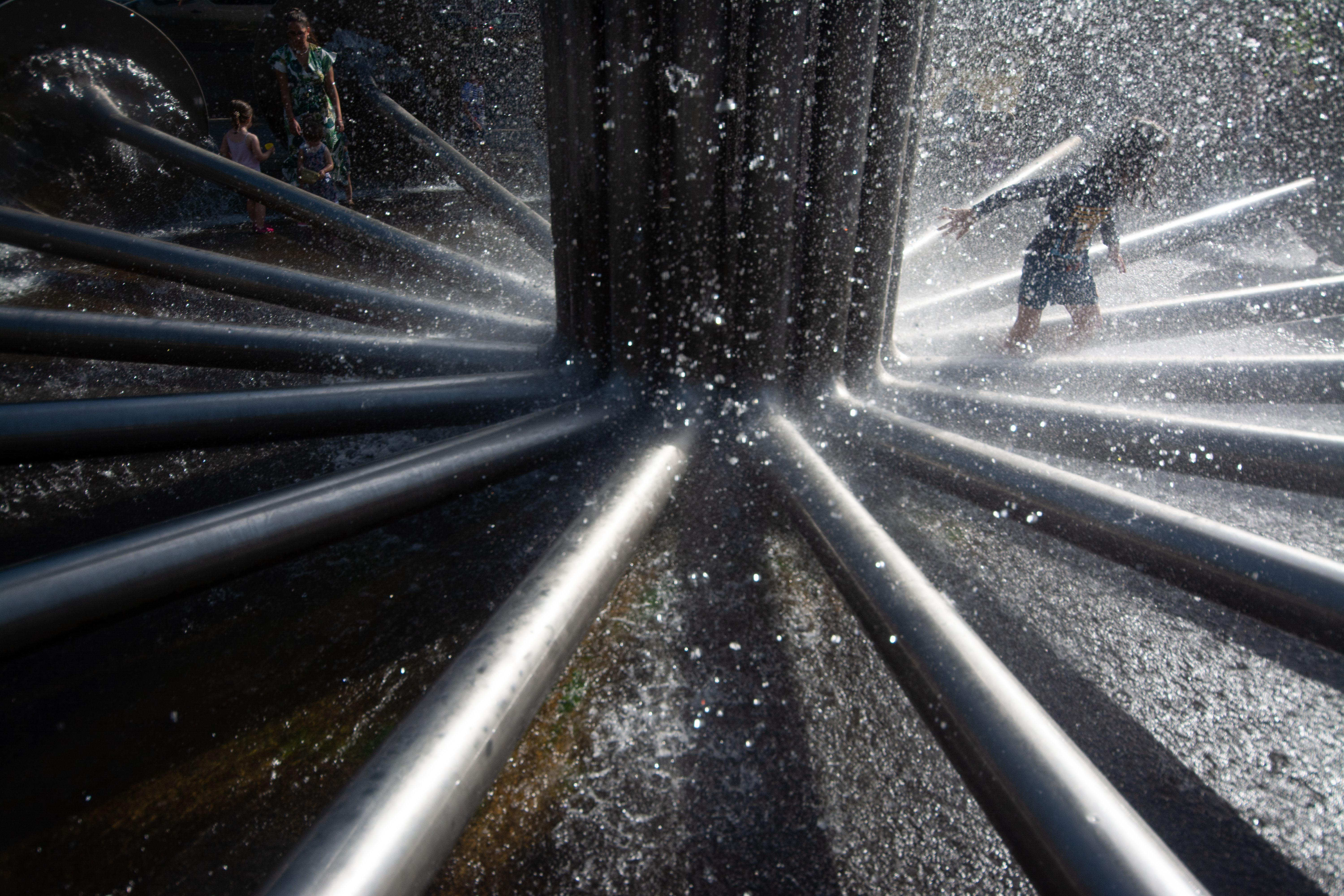 Um menino se refresca com água em uma fonte de água durante a onda de calor que continua em Colônia, Alemanha / Ying Tang/NurPhoto /Getty Images
