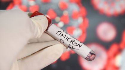 Nesta ilustração fotográfica, um profissional de saúde usando luvas segurando tubos de amostra de teste rotulados como 'variante COVID-19 Omicron' na frente de uma tela