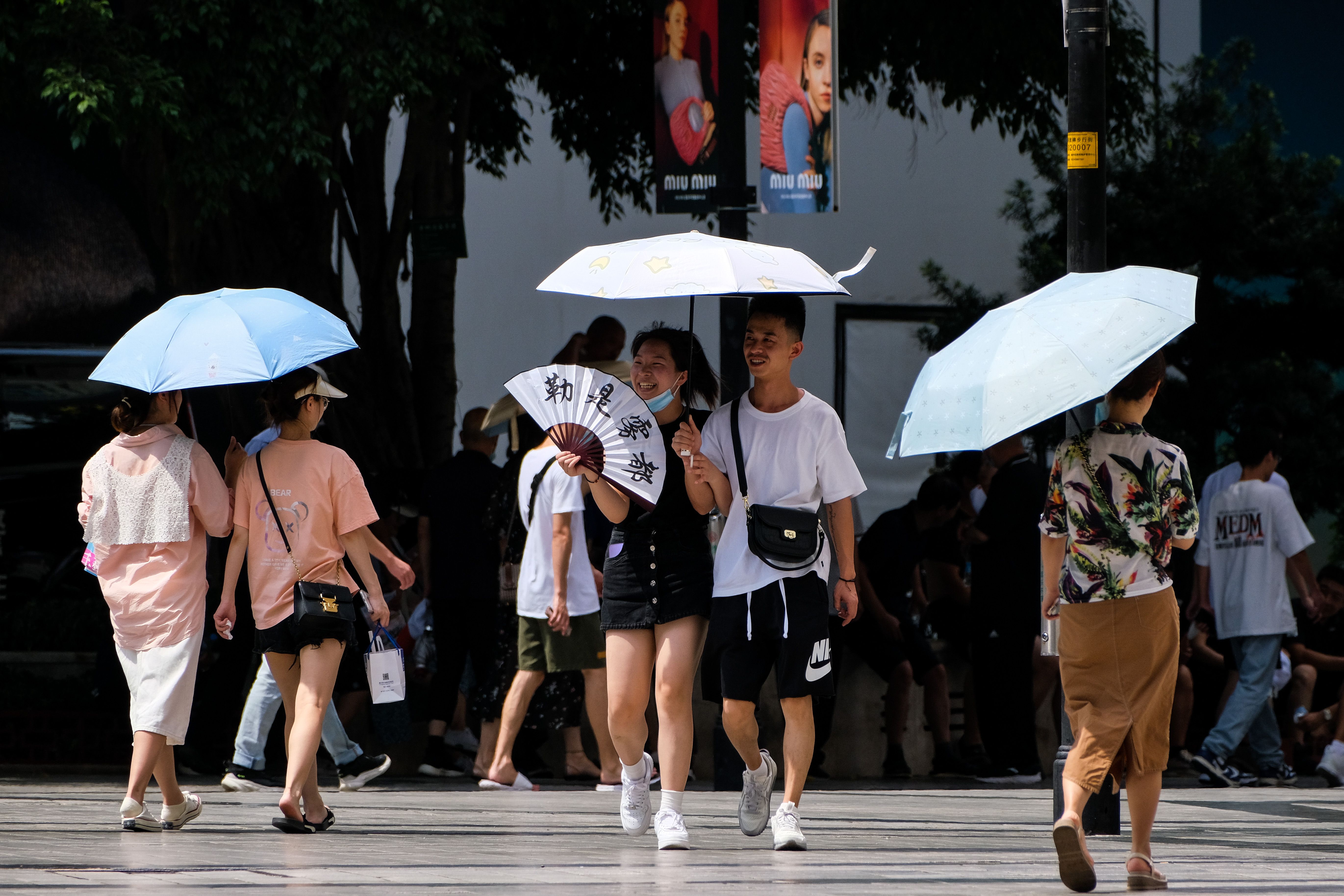 Pessoas com guarda-chuvas andam na rua em meio a alta temperatura em Chongqing / China News Service via Getty Ima