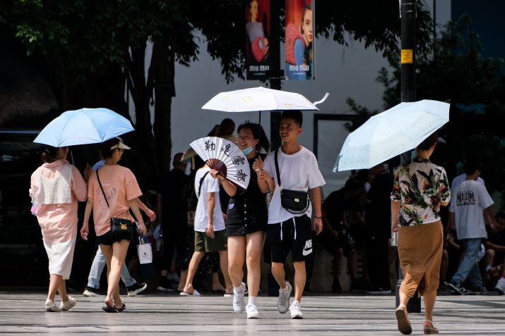 Pessoas com guarda-chuvas andam na rua em meio a alta temperatura em Chongqing / China News Service via Getty Ima