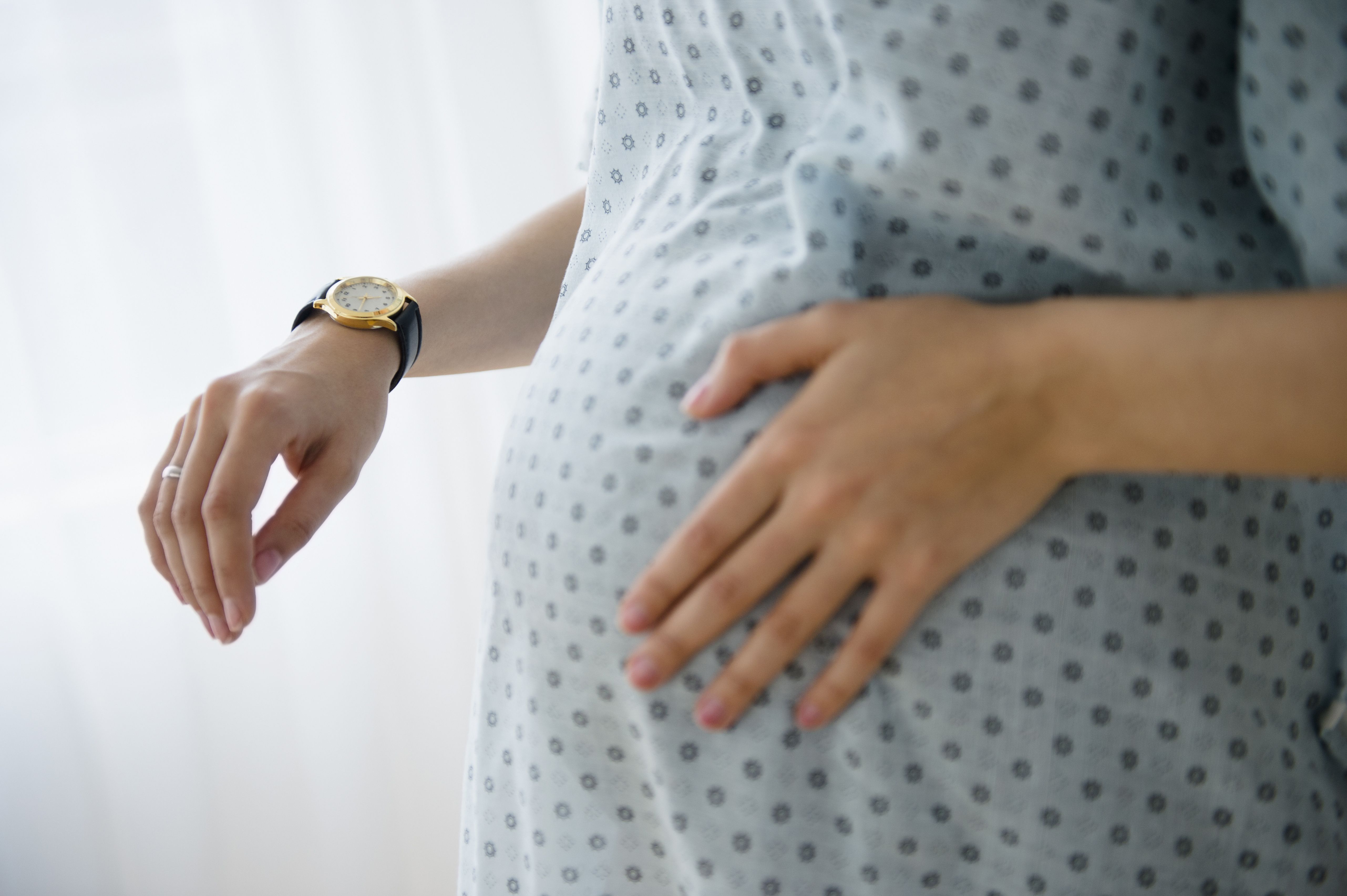 Mulher grávida com roupão de parto passando a mão na barriga