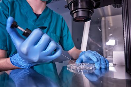 Um pesquisador manipulando material genético sob um microscópio