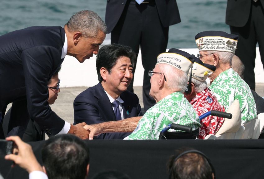 Depois de fazer discursos em Pearl Harbor, no Havaí, em 2016, Abe e o presidente dos EUA, Barack Obama, conversam com veteranos que sobreviveram ao ataque japonês em 1941. No discurso, Abe ofereceu suas "sinceras e eternas condolências" por aqueles que morreram no ataque / Kyodo News/Getty Images