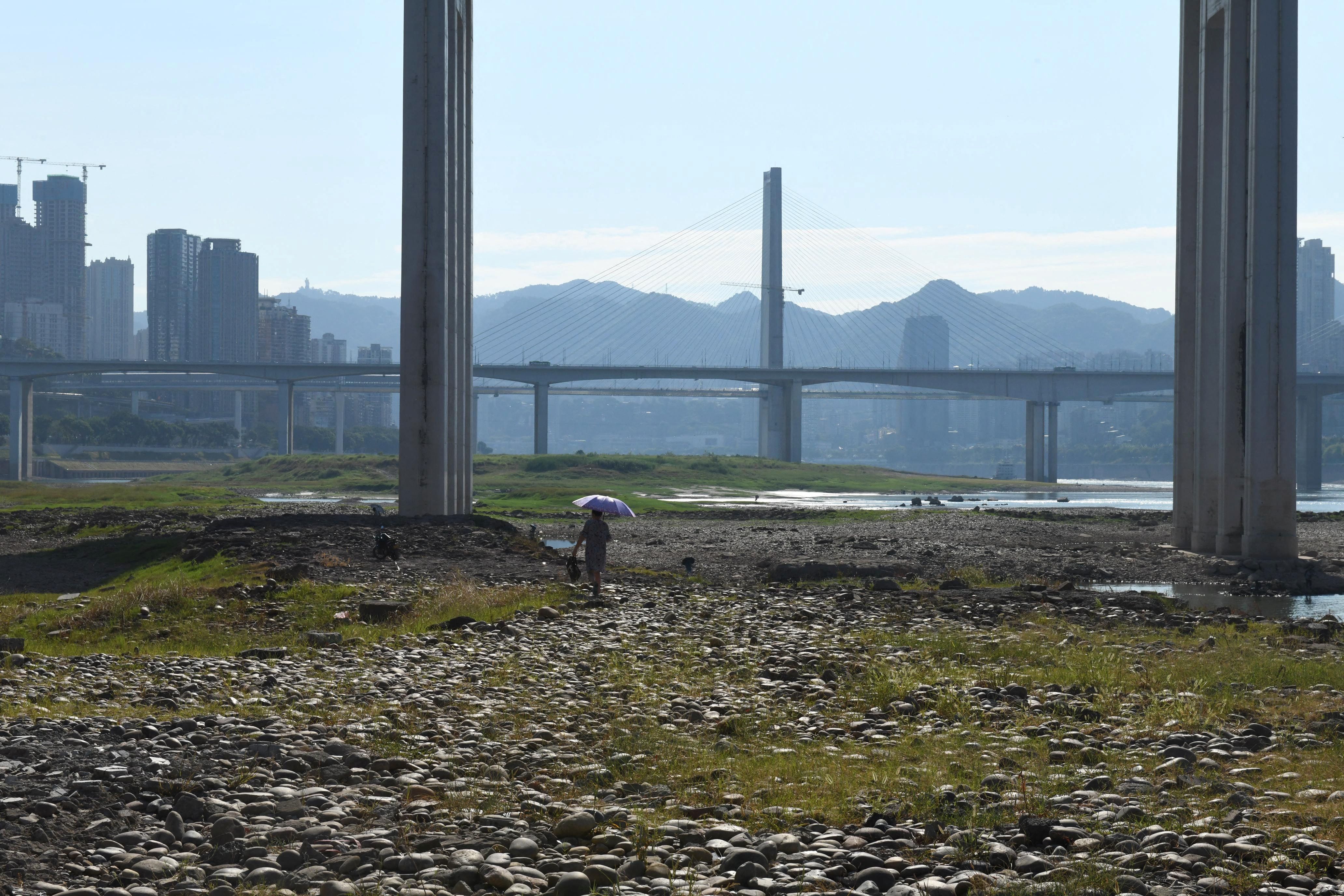 Mulher caminha no leito do rio Yangtze exposto em Chongqing